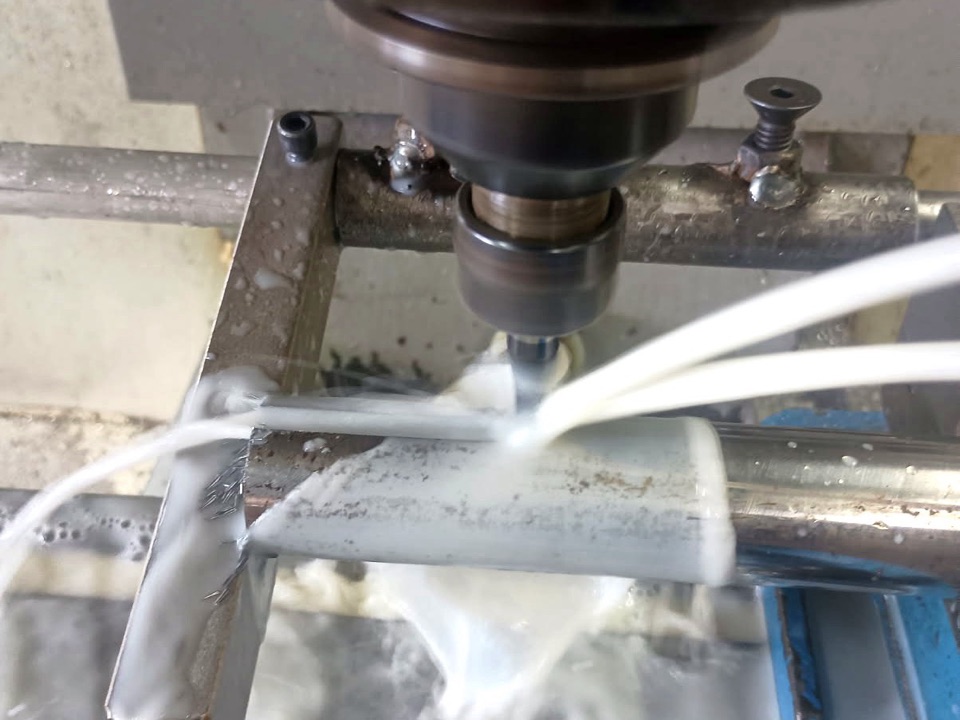 Square keyseat being milled into a round steel shaft under flood coolant, end mill entering from above